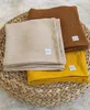 Three folded muslin blankets are stacked on a woven circular mat. Produktbild-Vorschau