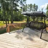 A swing chair with a canopy sits on a wooden deck, surrounded by trees and a grassy yard. Produktbild-Vorschau