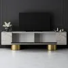 A modern TV stand with a marble-like finish and gold cylindrical legs, placed against a dark paneled wall. Produktbild-Vorschau