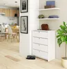 A white shoe cabinet with four drawers is placed in a hallway next to a kitchen. There are shelves above the cabinet with decorative items and clothing. A plant is next to the cabinet. Produktbild-Vorschau