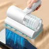 A hand is using a white handheld vacuum cleaner on a beige surface, with an internal diagram showing dust and particles being drawn in. The diagram also shows blue arrows indicating suction and a cross-section of a surface with a textured pattern. Náhľad obrázku produktu
