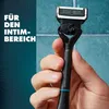 A hand holding a black razor with a blue accent against a teal tiled background. Produktbild-Vorschau
