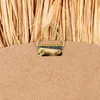 A close-up view of the back of a round wall mirror, showing the hanging hardware attached to the wooden backing and the edge of the raffia material. Produktbild-Vorschau