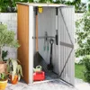 A garden shed filled with gardening tools, located outdoors next to a wall and plants. Podgląd zdjęcia produktu