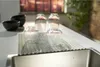 Glasses and bowls are drying on a dish rack next to a sink. Voir les images du produit