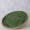 A green ceramic plate with a carved pattern on a light gray and white background. Produktbild-Vorschau