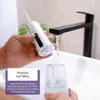 A hand is filling a water flosser with water from a faucet. Produktbild-Vorschau