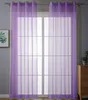 Two sheer purple curtains hang in front of a window with a grid pattern. A framed picture is on the left wall, and a wooden dresser with a potted plant is on the right.