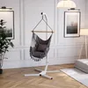 A hanging chair with a stand is set up in a well-decorated living room with artwork and a floor lamp. Produktbild-Vorschau