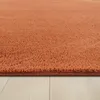 A close-up view of a textured orange rug on a light wooden floor. Produktbild-Vorschau