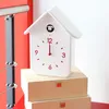 A white cuckoo clock with red accents is displayed on top of two wooden boxes. Anteprima dell’immagine prodotto