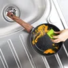 A hand is cleaning a frying pan in a sink. Podgląd zdjęcia produktu