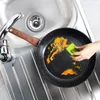 A person is cleaning a frying pan in a sink. Produktbild-Vorschau