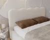 A close-up view of a bed with a textured headboard and two brown pillows. Náhled obrázku produktu