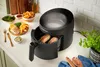 A Russell Hobbs air fryer is shown on a kitchen counter, with food and utensils arranged around it. Produktbild-Vorschau