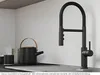 A black kitchen faucet is shown in a modern kitchen setting with a teapot and cups. Produktbild-Vorschau