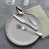 A place setting with a plate, fork, knife, and spoon on a textured gray surface, with a green napkin to the side. Anteprima dell’immagine prodotto