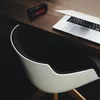 A digital alarm clock and a laptop are on a wooden desk next to a modern chair. Produktbild-Vorschau
