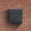 A dark gray mailbox mounted on a red brick wall. Náhľad obrázku produktu
