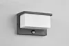 A modern outdoor wall light with a motion sensor, mounted on a light gray wall. Voir les images du produit