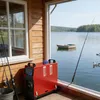 A red diesel heater is placed on a wooden deck next to a lake, with fishing rods nearby. Produktbild-Vorschau
