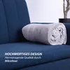 A rolled-up blanket with a dot pattern is placed on a blue sofa. Text overlays describe the product's quality and design. Produktbild-Vorschau