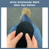 Hands holding a black sock, demonstrating the seam over the toes. A person's legs and feet in jeans and shoes are visible in the background. Produktbild-Vorschau
