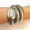 A close-up shot of a woman's arm wearing a silver snake-shaped watch. Podgląd zdjęcia produktu