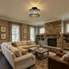 A well-decorated living room with a fireplace, sofas, and a coffee table, featuring the ceiling light. Voir les images du produit