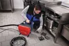 A man is using a pipe cleaning machine in a commercial kitchen. Podgląd zdjęcia produktu