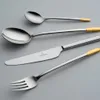 A set of cutlery with silver and gold accents against a plain gray background. Produktbild-Vorschau