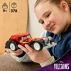 A young girl is holding a red toy car. Voir les images du produit