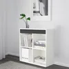 A white shelving unit with books and binders inside, placed against a white wall with a framed picture above. Produktbild-Vorschau