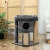 A cat tree with a scratching post and a small house is placed on a wooden floor in a room with a folding screen and a plant in the background. Produktbild-Vorschau