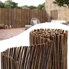 A garden scene with a bamboo fence, wooden deck, and outdoor furniture. A close-up of the bamboo fence material is shown in the foreground. Produktbild-Vorschau