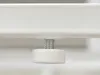 A close-up view of a white adjustable foot with a silver screw attached to a white surface. Náhľad obrázku produktu