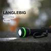 A close-up of a black and green LED flashlight emitting a bright light, placed on a textured surface. Podgląd zdjęcia produktu