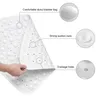A hand is holding a white bath mat, showing its texture and features. Voir les images du produit