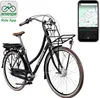 A black electric bicycle with a brown saddle and handlebars, shown in a studio setting with a white background. A smartphone displaying a navigation app is placed to the right of the bicycle. Produktbild-Vorschau