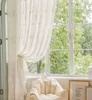 A cozy interior scene with sheer curtains, a beanbag chair, and a framed picture by a window. Produktbild-Vorschau