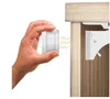 A hand is holding a white magnetic lock and approaching a cabinet door with a white lock mechanism attached. Voir les images du produit