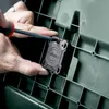 A person is using a screwdriver to attach a black device with the Metabo logo to a green plastic surface. Voir les images du produit