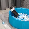 A small rabbit is playing in a blue ball pit filled with colorful balls. Produktbild-Vorschau