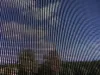 A close-up view of a screen displaying a pattern of vertical lines, with a blurred background suggesting trees and sky. Produktbild-Vorschau