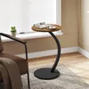 A small round side table with a vintage wood-look top and a black metal base is placed next to a brown armchair by a window. A small potted plant sits on the windowsill. Produktbild-Vorschau