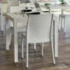 A white rattan-style table and chairs set in an indoor setting with a wooden floor. Produktbild-Vorschau