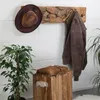 A rustic wooden coat rack with a hat and jacket hanging on it, placed against a white brick wall. Produktbild-Vorschau