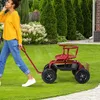 A woman is pulling a red garden cart with a seat in a grassy yard. Podgląd zdjęcia produktu