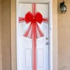 A white door decorated with a large red bow and streamers, likely for a holiday or special occasion. Náhled obrázku produktu