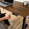 A person's hand is pressing buttons on a height-adjustable desk control panel. Náhled obrázku produktu